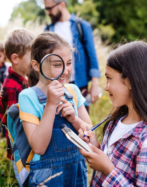 Group of school children with teacher on field trip in nature, learning science.